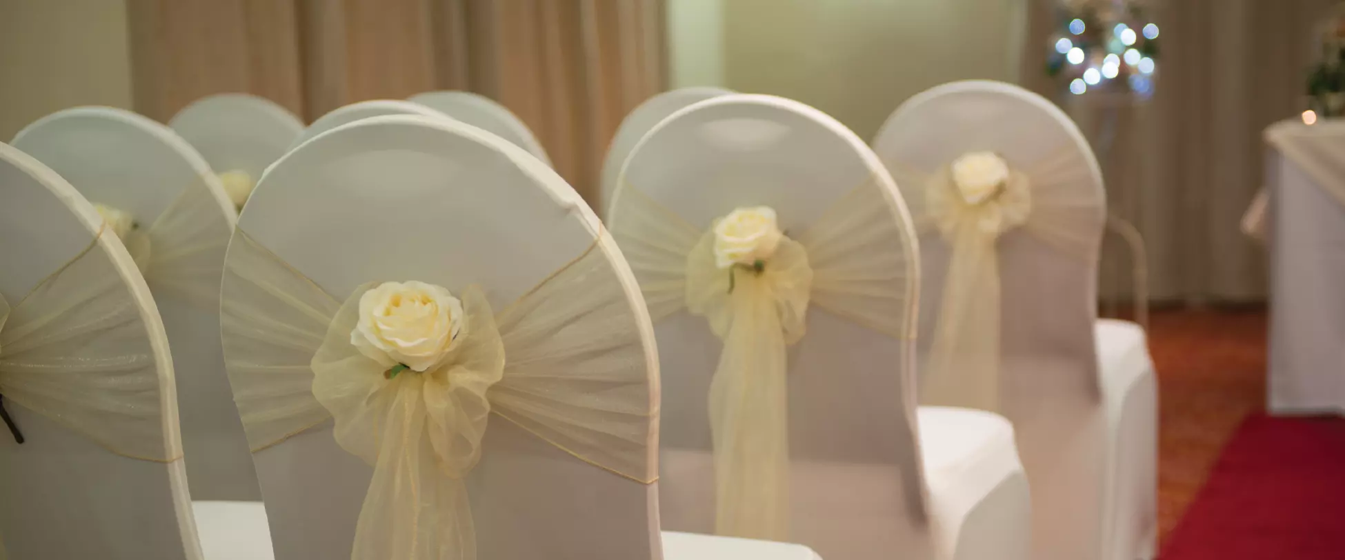 White chairs set up for a wedding, with yellow bows tied around them..